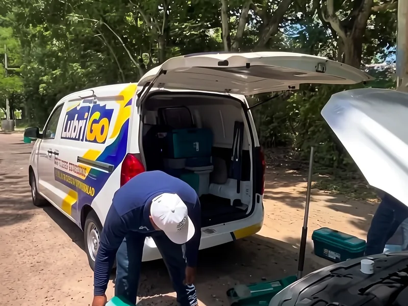 Técnico de LubriGo preparando el tapete de trabajo junto al carro del cliente